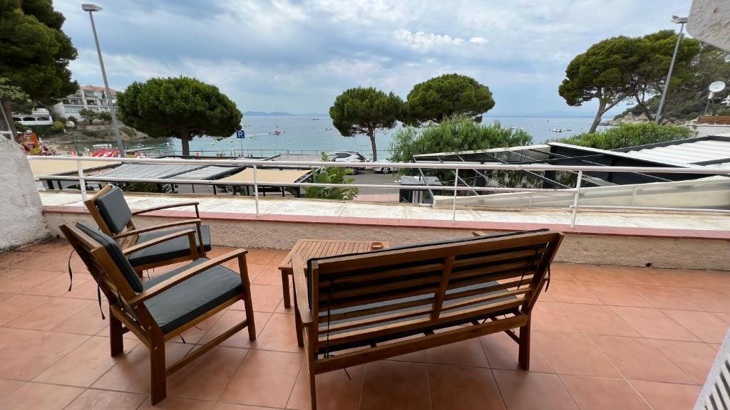 eine Terrasse mit einer Bank, einem Tisch und einem Laptop in der Unterkunft Precioso apartamento moderno en primera linea del mar in Roses