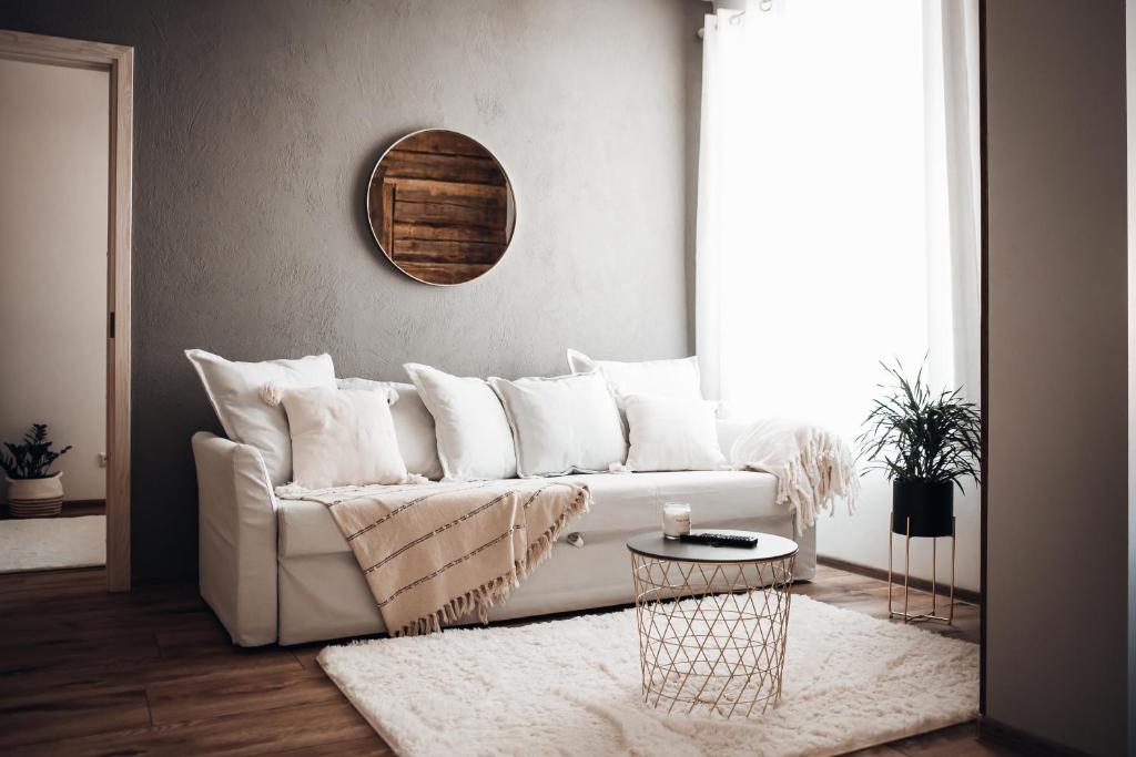a living room with a white couch and a mirror at Stylish and cozy old town apartment in Võru