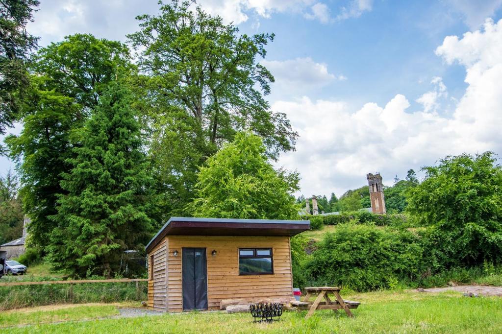 a small wooden cabin in a field with a picnic table at Craigengillan Mini Lodge in Dalmellington