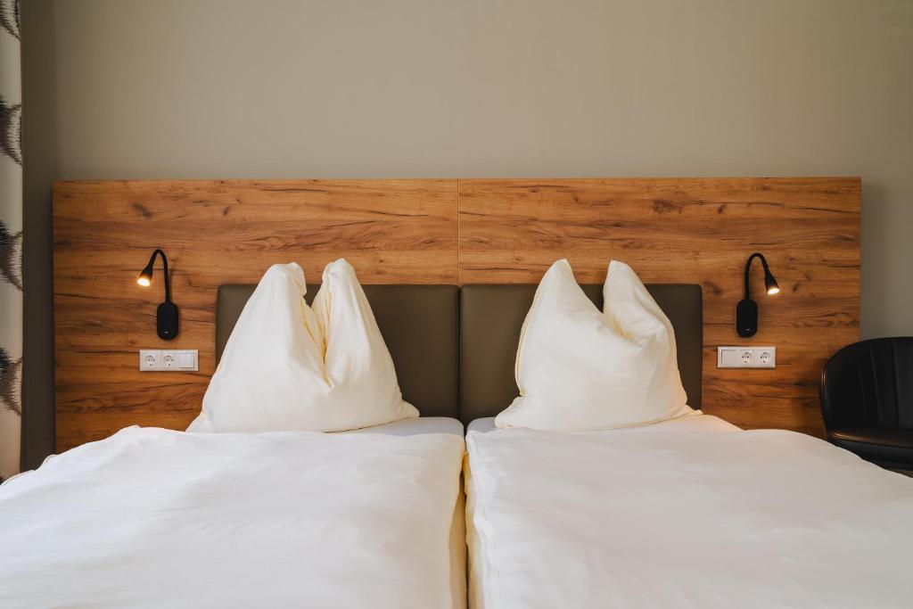 - 2 lits avec des oreillers blancs placés côte à côte dans l'établissement Die Pension Galle, à Arnoldstein