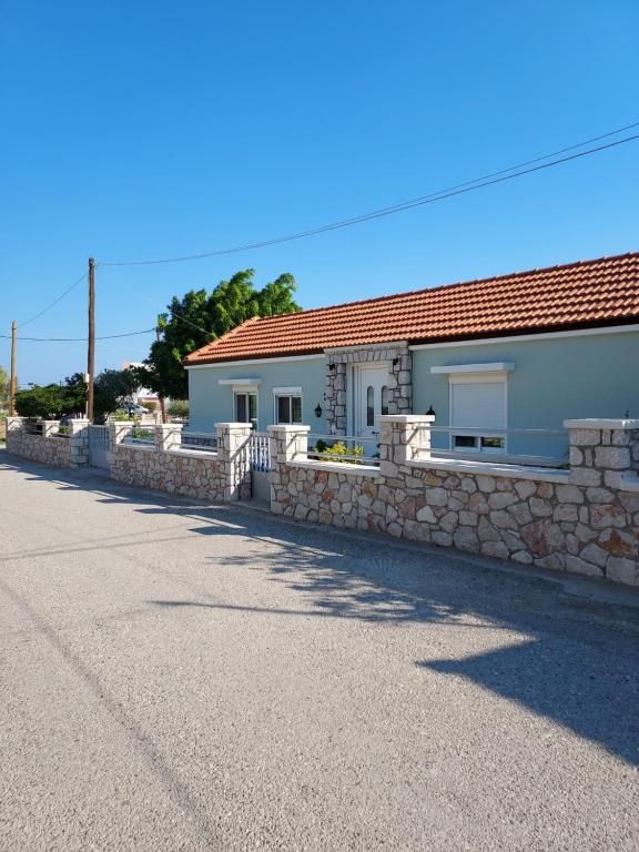 ein Haus mit einer Steinmauer neben einer Straße in der Unterkunft Anastasia's holiday house with garden in Ialyssos