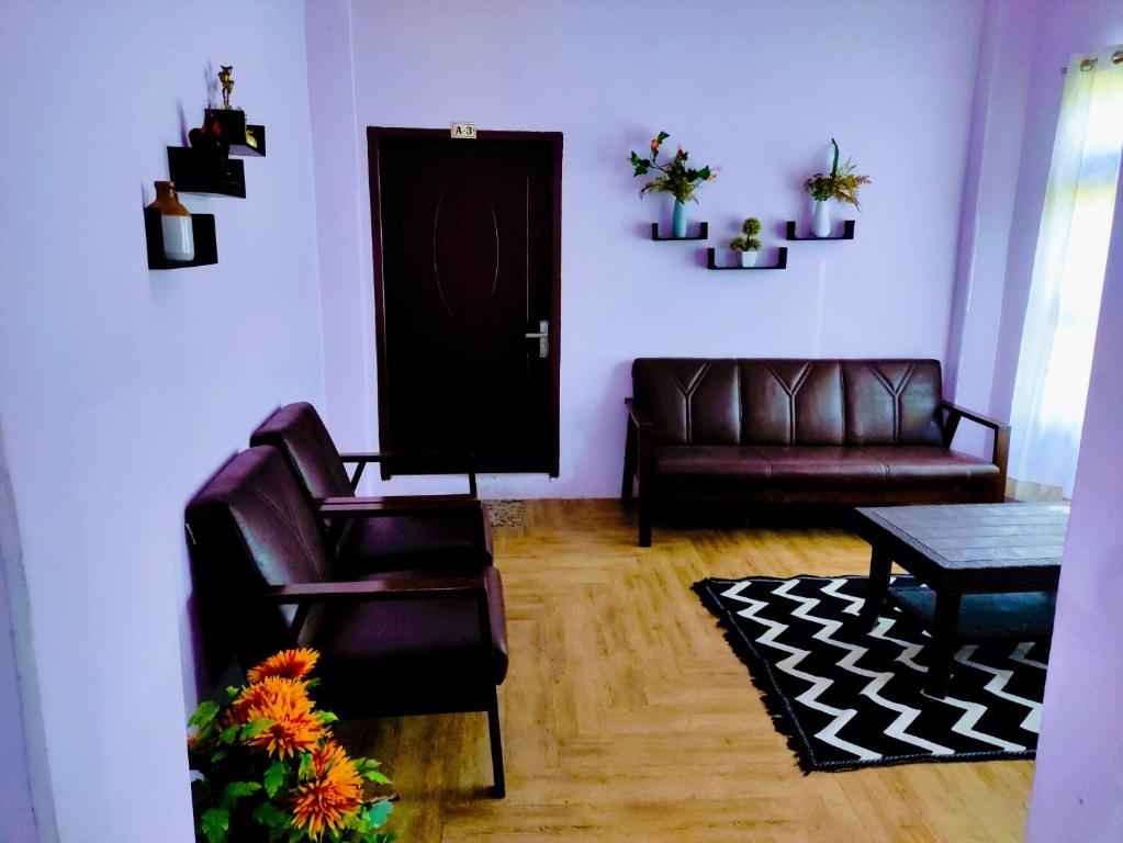 a living room with two leather chairs and a door at Chawngthu Lodge in Āīzawl