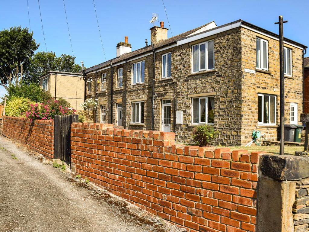 a brick wall in front of a house at Yorkshire Cottage in Clayton West