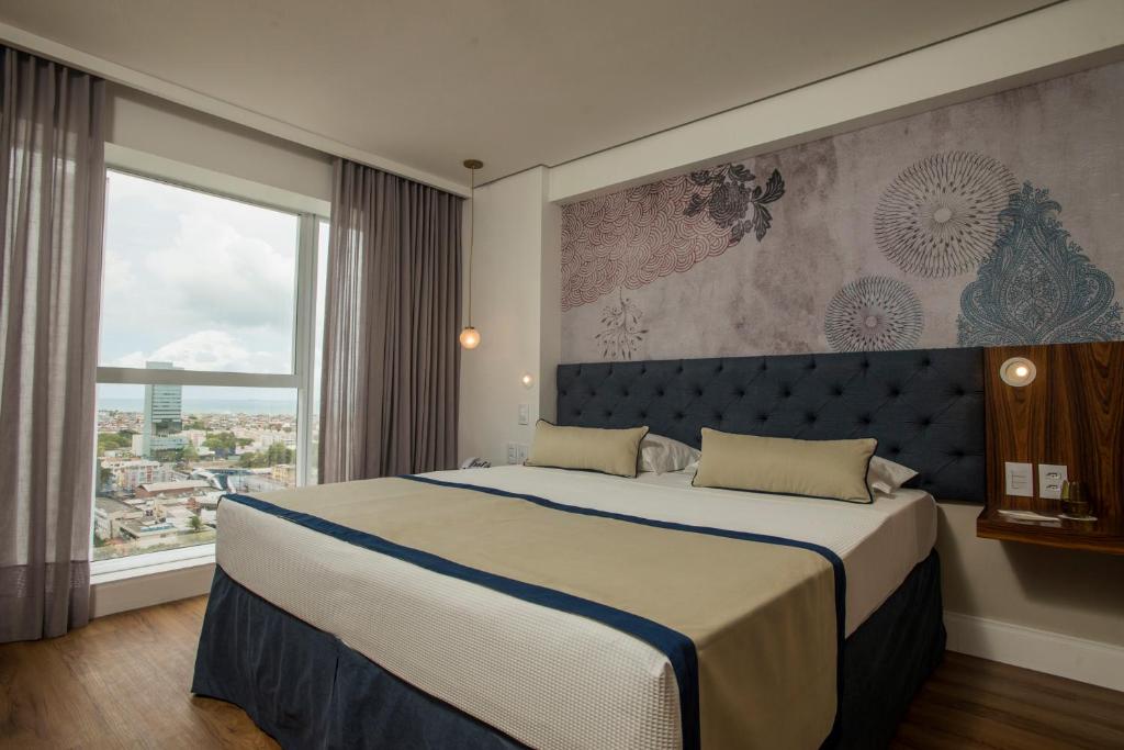 a bedroom with a large bed and a large window at Hotel Luzeiros Recife in Recife