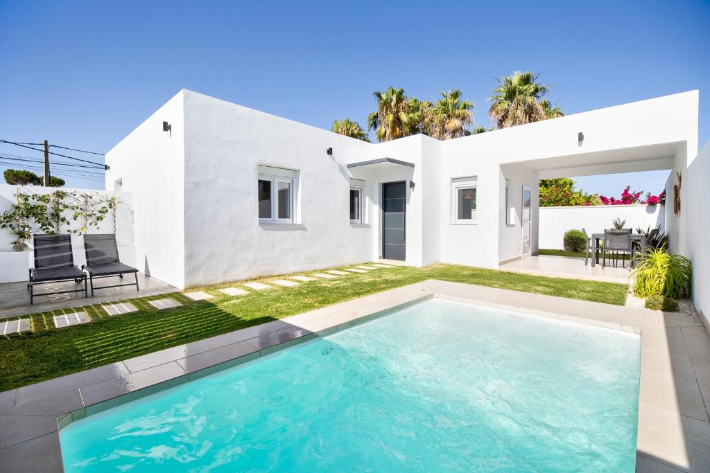 una casa blanca con piscina frente a ella en Casa Piscina Cubierta Climatizada 3, en Chiclana de la Frontera