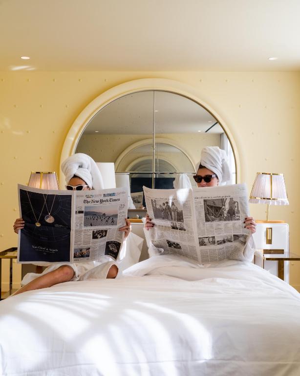 two people sitting on a bed reading newspapers at 9Confidentiel in Paris