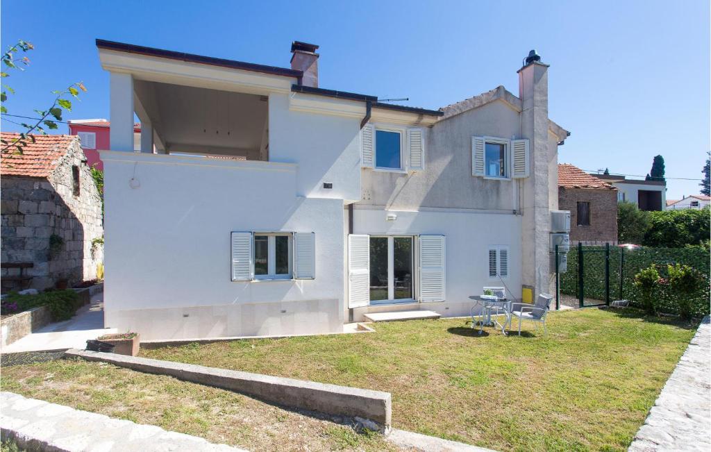 uma casa branca com um quintal à frente em Beautiful Apartment In Podgrade With Jacuzzi em Slime