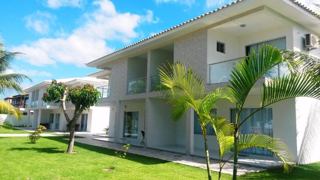 una casa blanca con palmeras delante en Porto Luar, en Porto Seguro