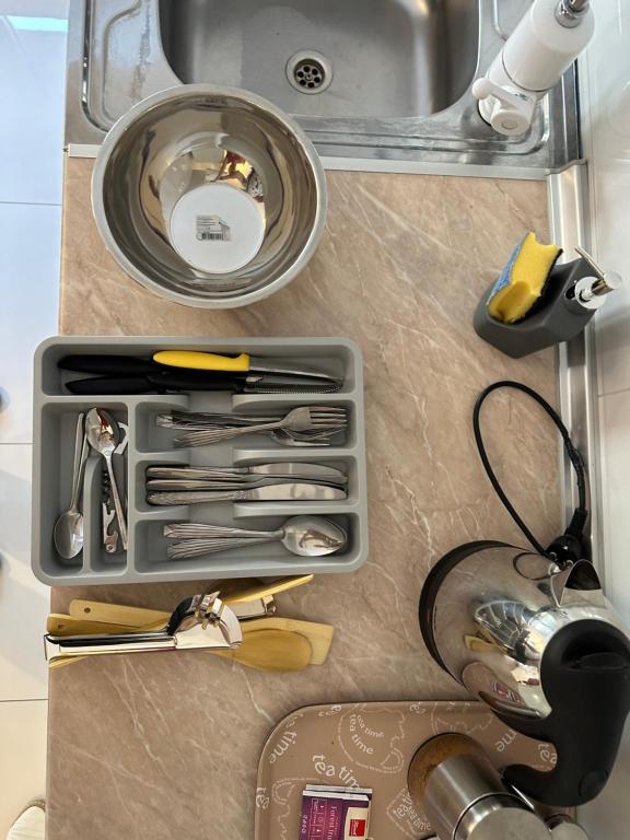 a container of kitchen utensils sitting next to a sink at Skopje Apartments near central Bus Station JK APARTMENTS in Skopje