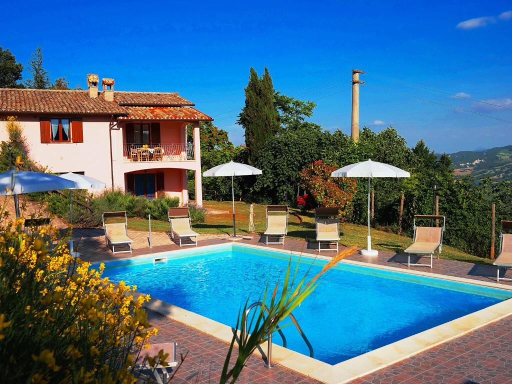 a pool with chairs and umbrellas in front of a house at Luxurious Villa in Acqualagna with Swimming Pool in Acqualagna
