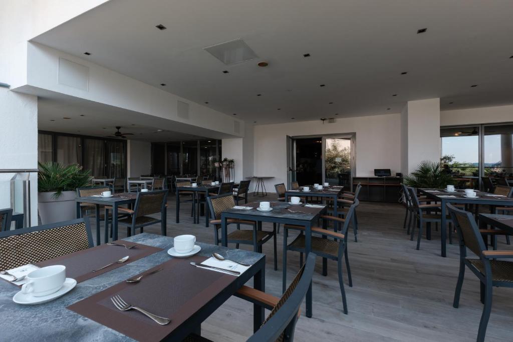 a restaurant with wooden tables and chairs and windows at Eurostars Queen of Montenegro in Budva