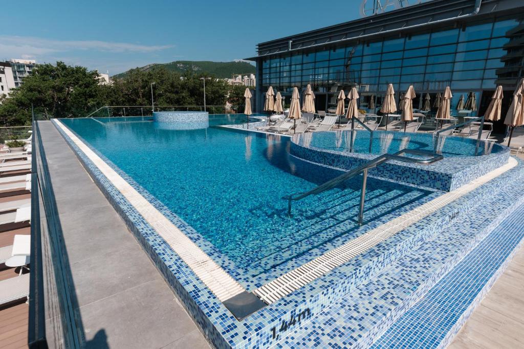 a large swimming pool with chairs and umbrellas at Eurostars Queen of Montenegro in Budva