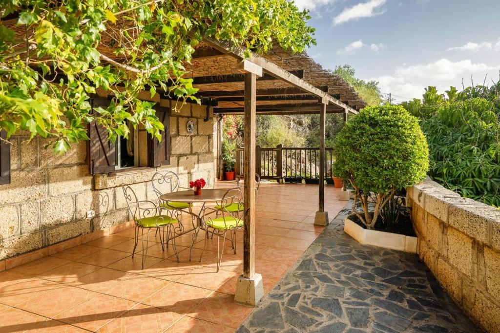 patio con tavolo e sedie sotto un pergolato di Holiday home in Malpais de Candelaria with a terrace a Bence