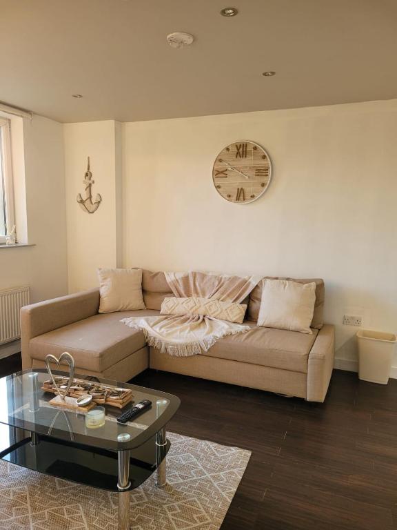 ein Wohnzimmer mit einem Sofa und einer Uhr an der Wand in der Unterkunft Amazing London 1 BR Flat in Astral House AS18 in Norbury