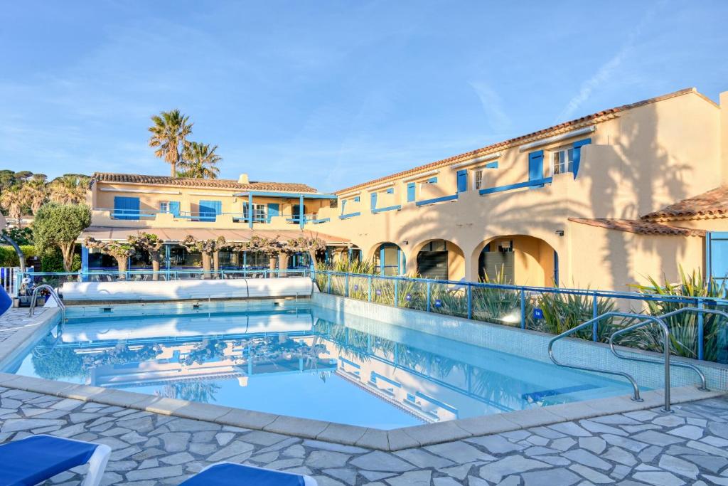 une piscine en face d'un bâtiment dans l'établissement Hôtel La Nartelle, à Sainte-Maxime