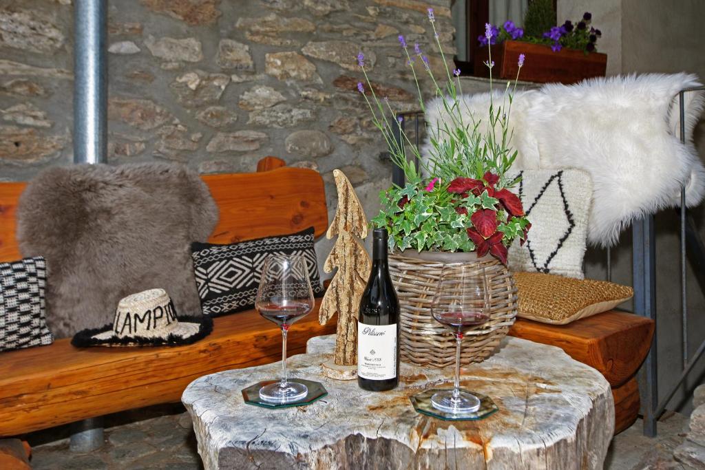 a table with two wine glasses and a vase of flowers at Chalet Faure in Sauze dʼOulx