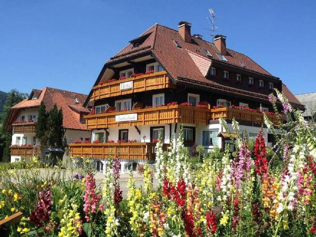 duży budynek z ogrodem kwiatów w obiekcie Hotel Zartenbach B&B w mieście Hinterzarten