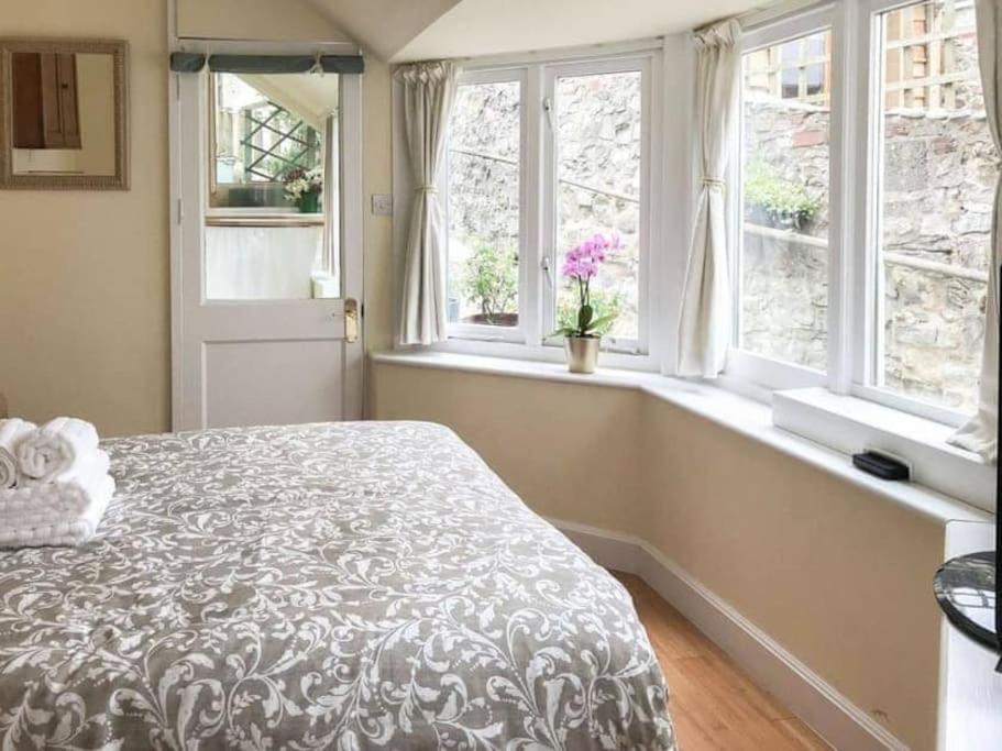 1 dormitorio con 1 cama grande y 2 ventanas en Lyme Clifftop Hideaway en Lyme Regis