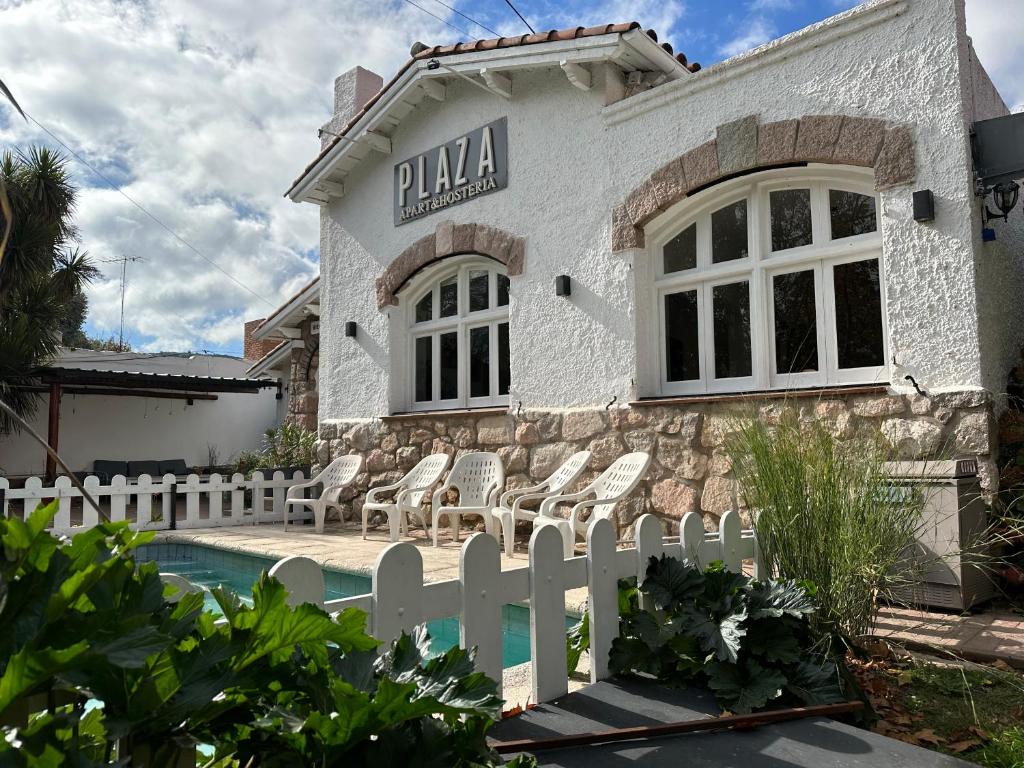 a white fence in front of a building with a pool at ApartHosteriaPlaza in La Cumbre