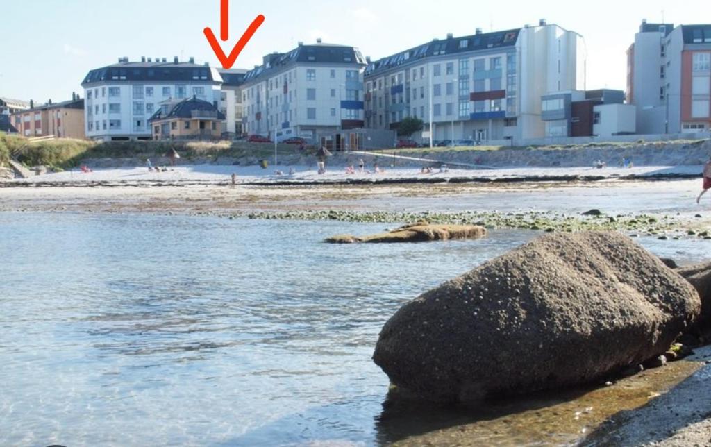 skała w wodzie obok plaży z budynkami w obiekcie San Ciprian Marinero by I Love Norte w mieście San Ciprián