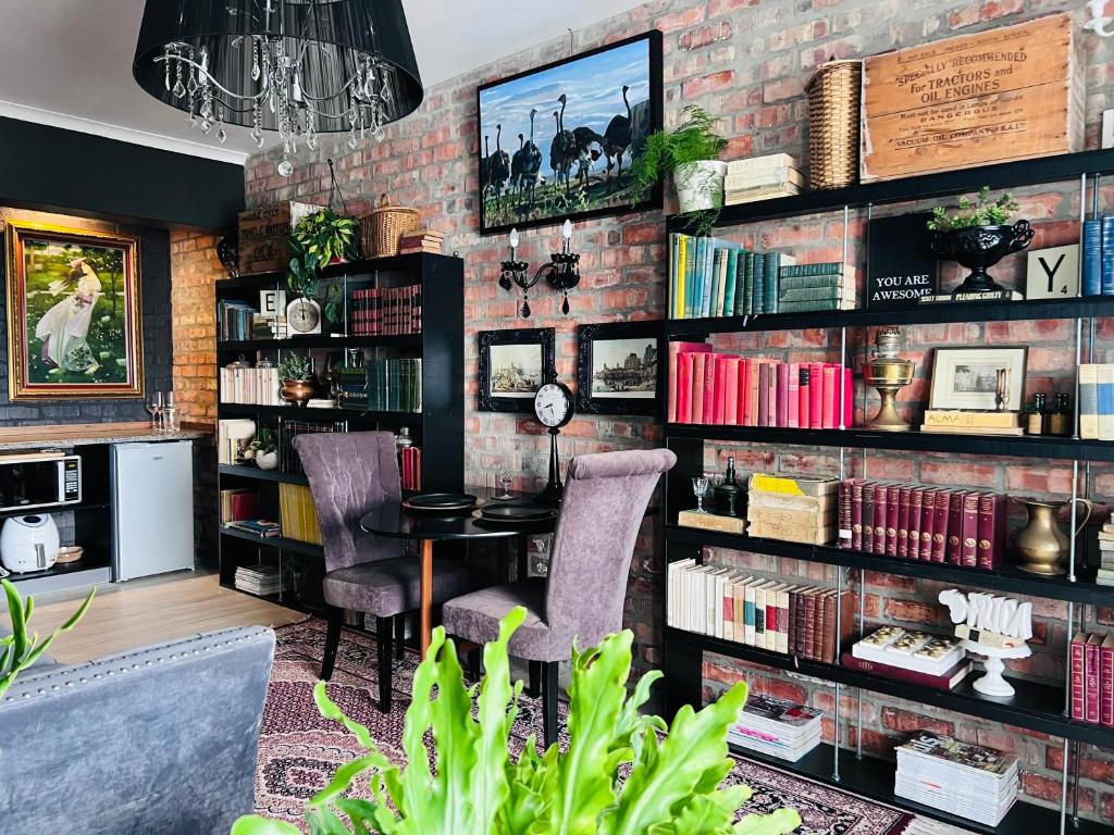 a room with a brick wall with a table and chairs at Royal Library Room in Mossel Bay