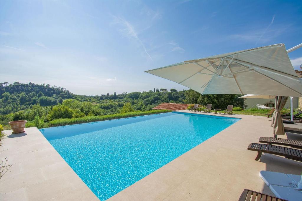 a swimming pool with an umbrella next to a house at Villa Fraiano in Palaia