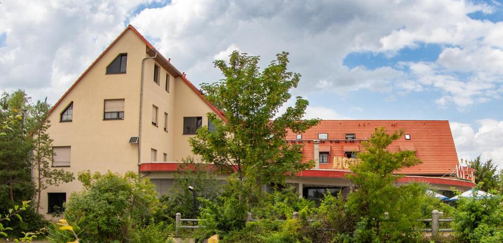 ein großes Gebäude mit rotem Dach und Bäumen in der Unterkunft WEST Hotel an der Sächsischen Weinstrasse in Radebeul