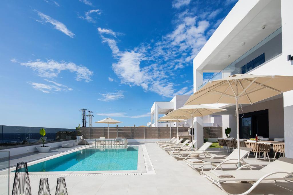 una piscina sul tetto di un edificio con sedie e ombrelloni di Babis Villa, a few meters away from the beach, By ThinkVilla a Panormos