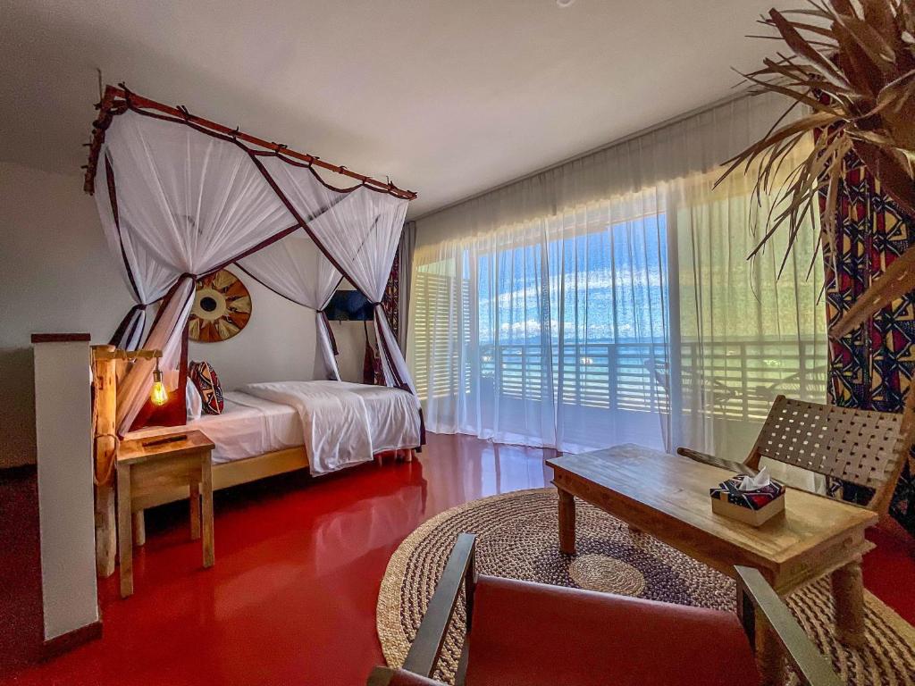 a bedroom with a canopy bed with a table and a couch at Maison Ylang Dive Center in Nosy Be
