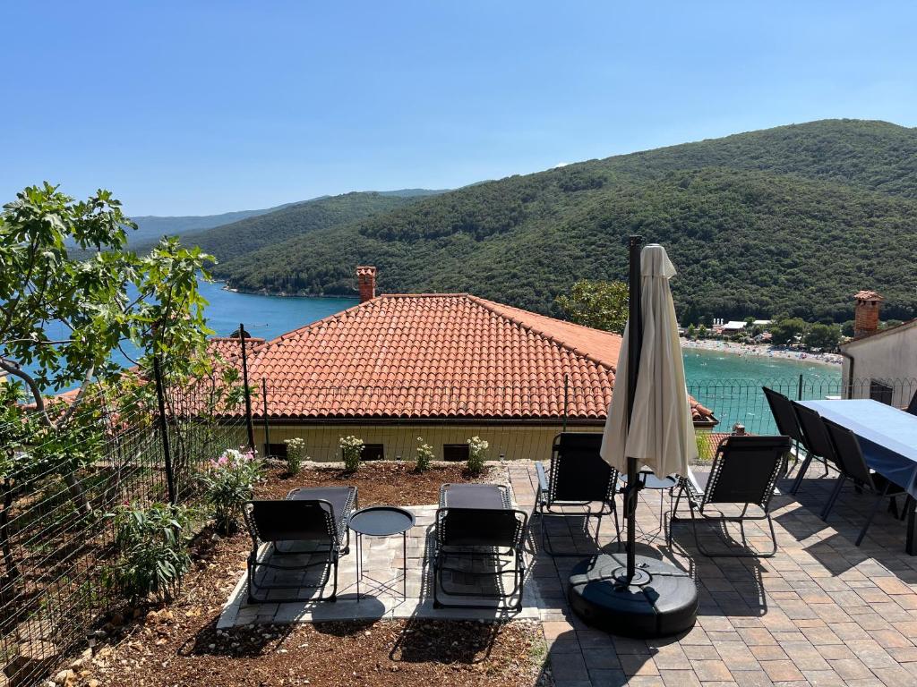a patio with a table and chairs and an umbrella at Apartments Zahtila - Berto in Rabac