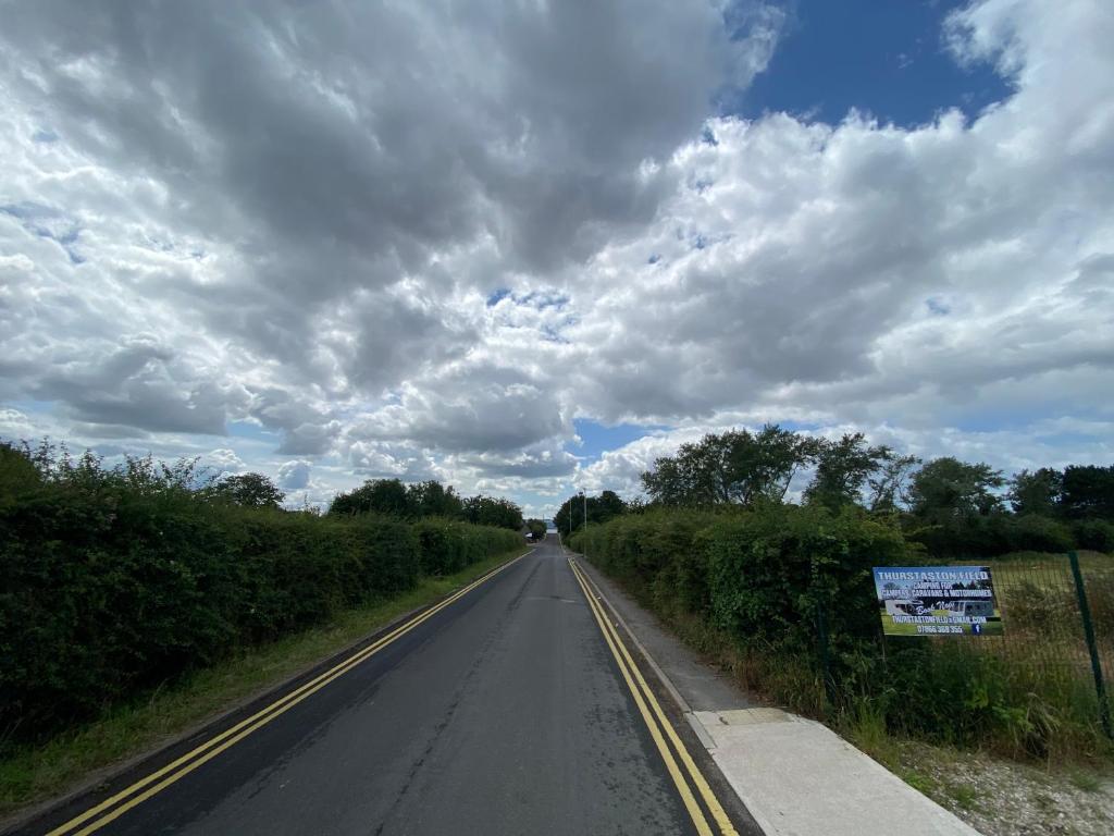 an empty road with a cloudy sky in the middle at Thurstaston Field in Thurstaston