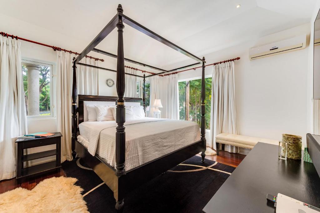 a bedroom with a four poster bed and windows at The Palms Resort in Saint James