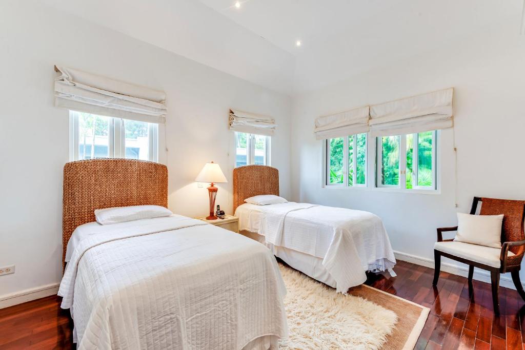 two beds in a white room with two windows at The Palms Resort in Saint James