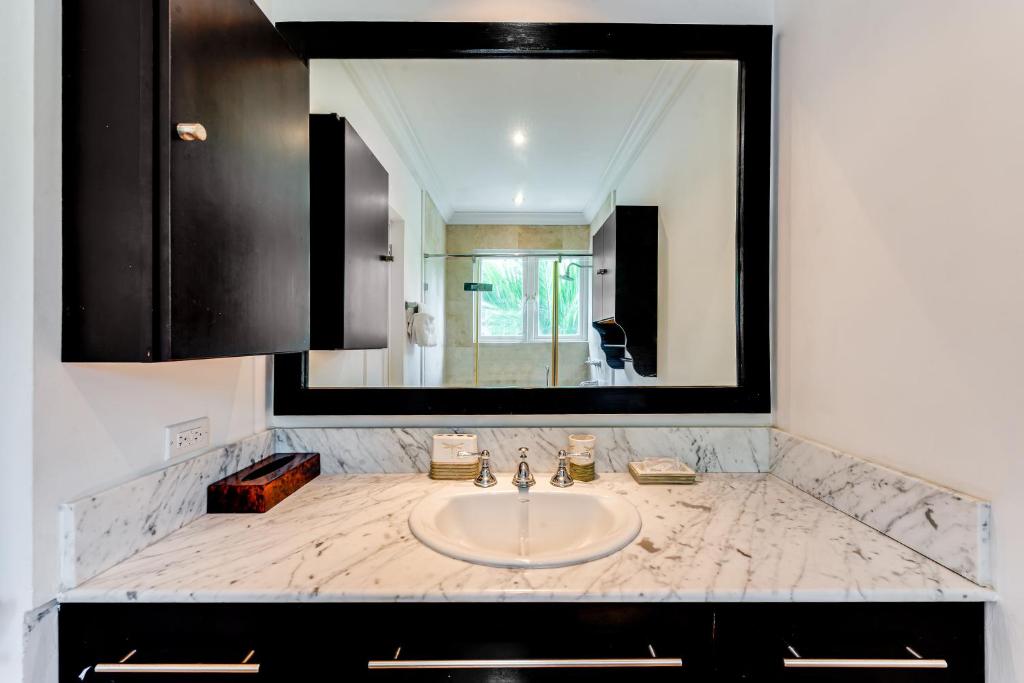 a bathroom sink with a large mirror above it at The Palms Resort in Saint James