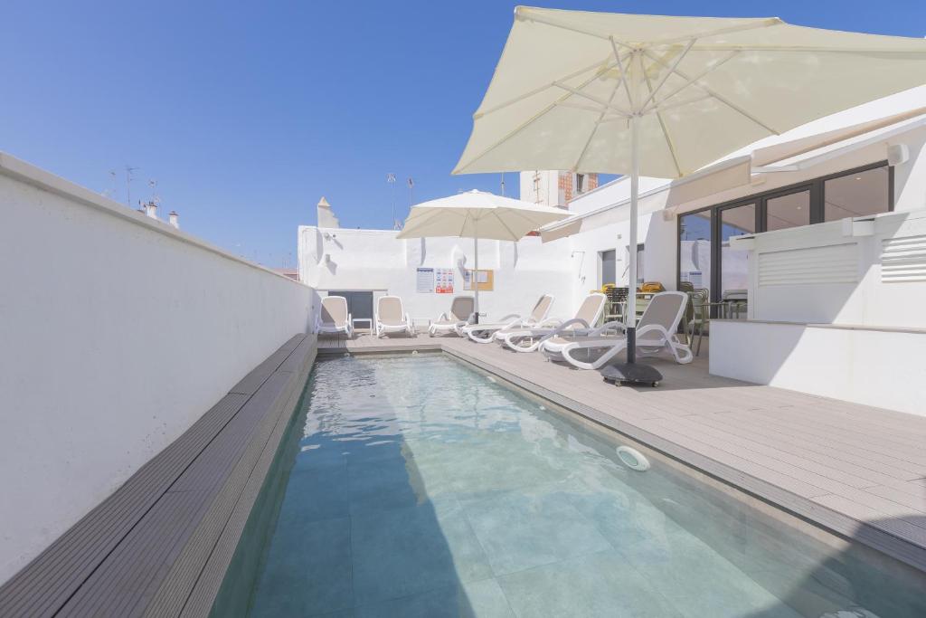 een zwembad met een parasol naast een huis bij Soho Boutique Columela in Cádiz