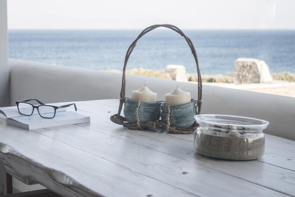 a table with glasses and candles on a table near the ocean at Paros Melodia Apartments in Logaras