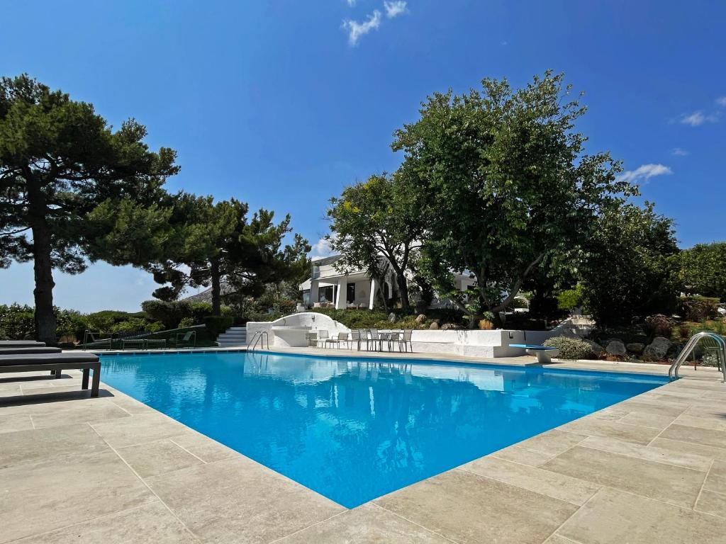 a swimming pool with a bench in front of a house at Villa Oasis with Large Pool Athenian Riviera Lagonissi in Lagonissi