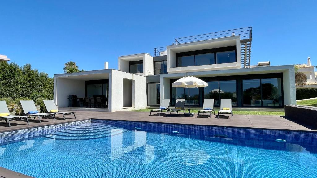 a villa with a swimming pool in front of a house at Passion by Check-in Portugal in Albufeira