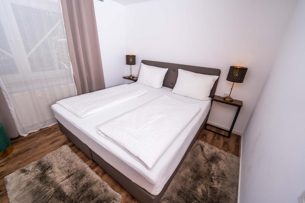 un letto con lenzuola e cuscini bianchi in una camera da letto di CityWohnungFN a Friedrichshafen