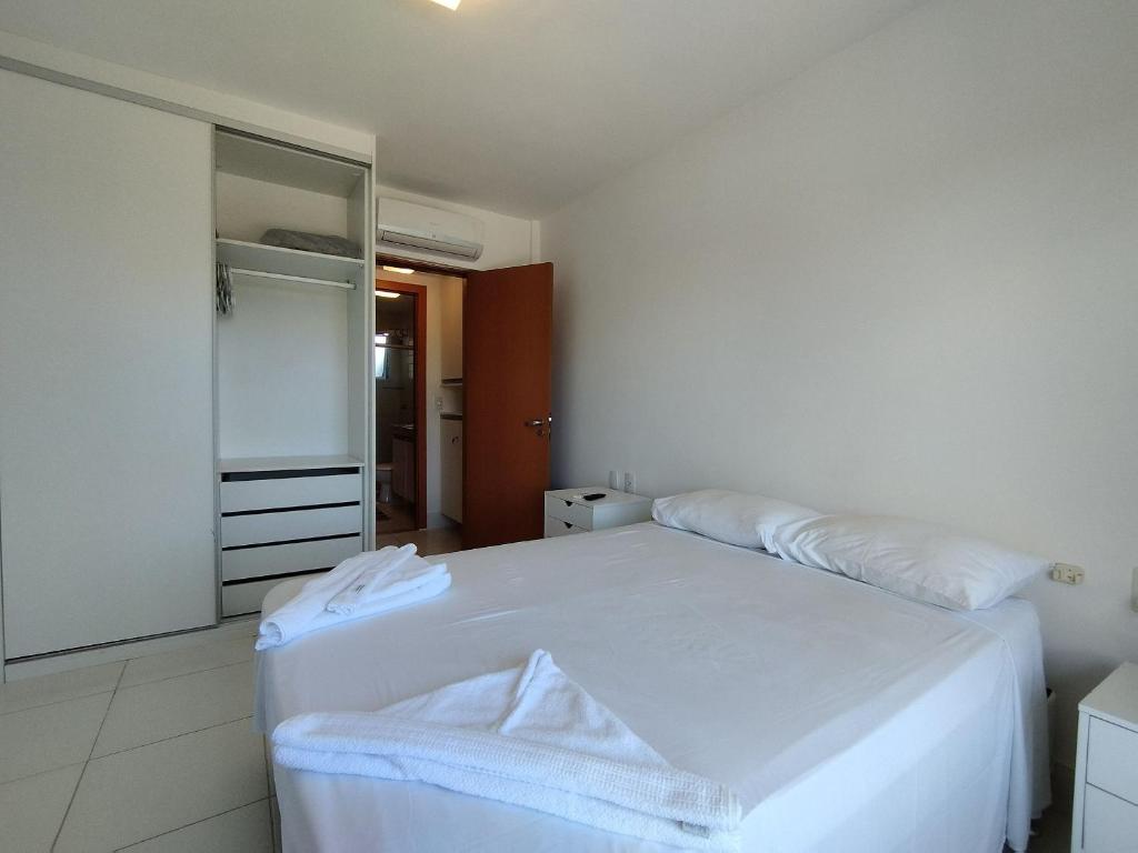 um quarto com uma cama branca e um espelho em Reserva Imbassaí Apartamento 1 quarto área de churrasco Bl2202 em Mata de São João