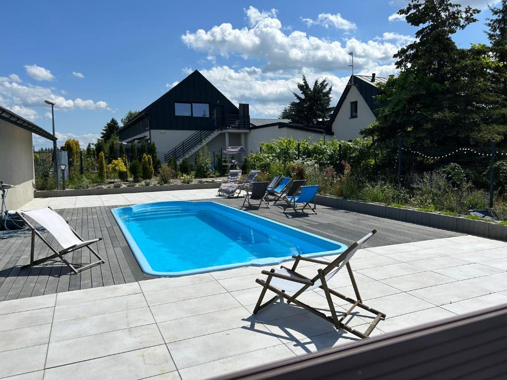 a swimming pool with two lawn chairs and a couple of chairs at Koniec Świata nowa stodoła in Mikołajki