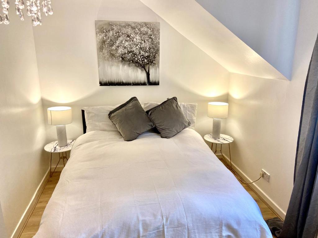 1 dormitorio con 1 cama blanca y 2 lámparas en London Studio Self Contained, Newly Furbished en Londres