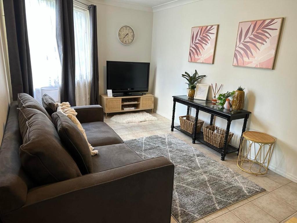 Il comprend un salon doté d'un canapé et d'une télévision à écran plat. dans l'établissement Affordable Inn, à Perth