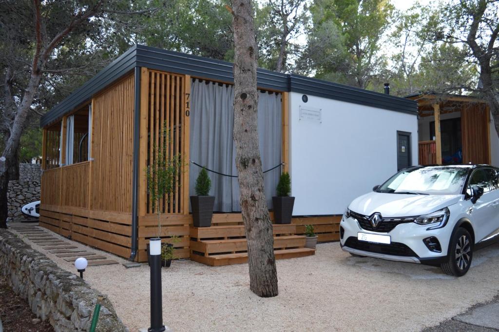 a small cabin with a car parked in front of it at Lucas Mobile Home - premium mobile home with terrace and patio in Drage