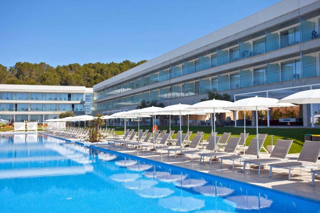 a swimming pool with chairs and umbrellas next to a building at Seth 55 Santo Tomas in Santo Tomás