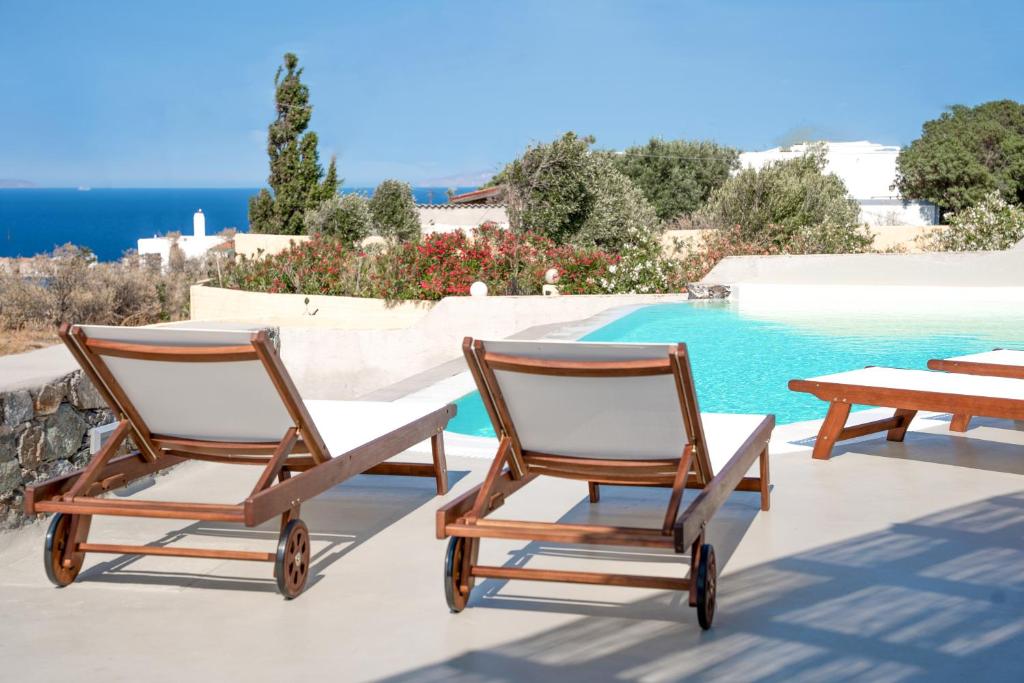 two chairs and a table next to a swimming pool at DIPOLIS luxury apartments Syros in Episkopíon