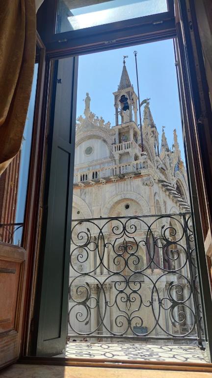 een raam met uitzicht op een gebouw met een klokkentoren bij Bellevue Luxury Rooms - San Marco Luxury in Venetië