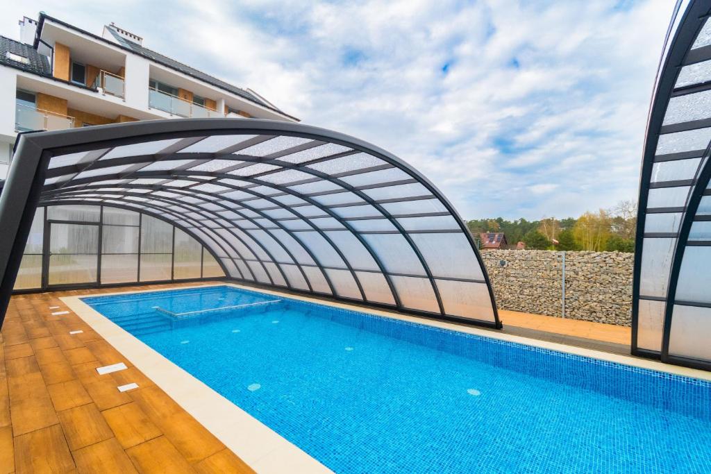 a swimming pool under an archway in a building at Flatbook Apartamenty - Sztutowo Baltic Garden in Sztutowo