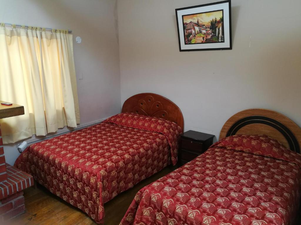 a hotel room with two beds and a window at Welcome Cusco Hostel in Cusco