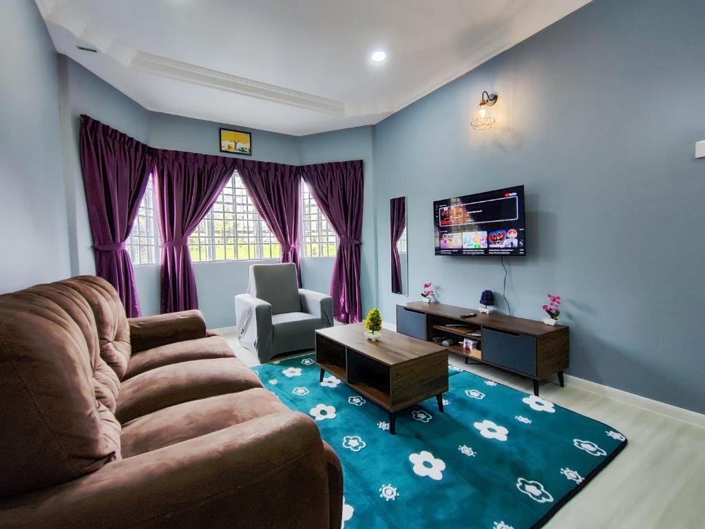 a living room with a couch and a tv at A One Holiday Apartment - PRO in Tanah Rata